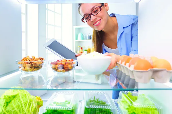 Portrait of female standing near open fridge full of healthy food, vegetables and fruits. Food Safety Level 1 Training Course